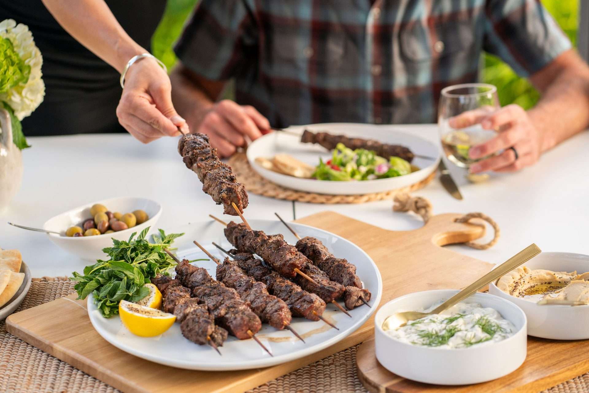 A plate of lamb skewers being enjoyed at an outdoor dinner
