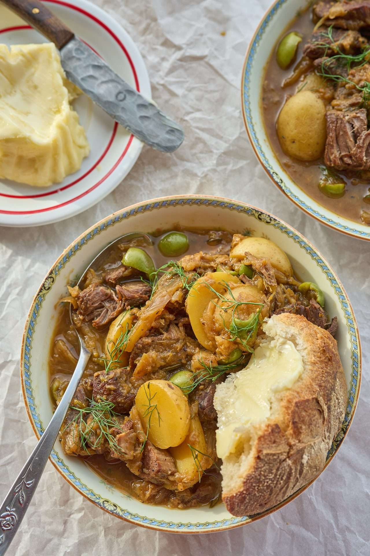 Slow-cooked American lamb stew with fennel and olives, featuring tender lamb, potatoes, and herbs in a rich, savory broth, served with crusty bread.