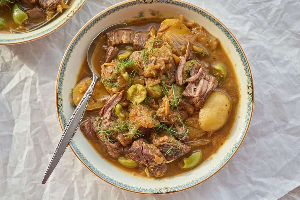 Slow-cooked American lamb stew with fennel and olives, featuring tender lamb, potatoes, and herbs in a rich, savory broth, served with crusty bread.