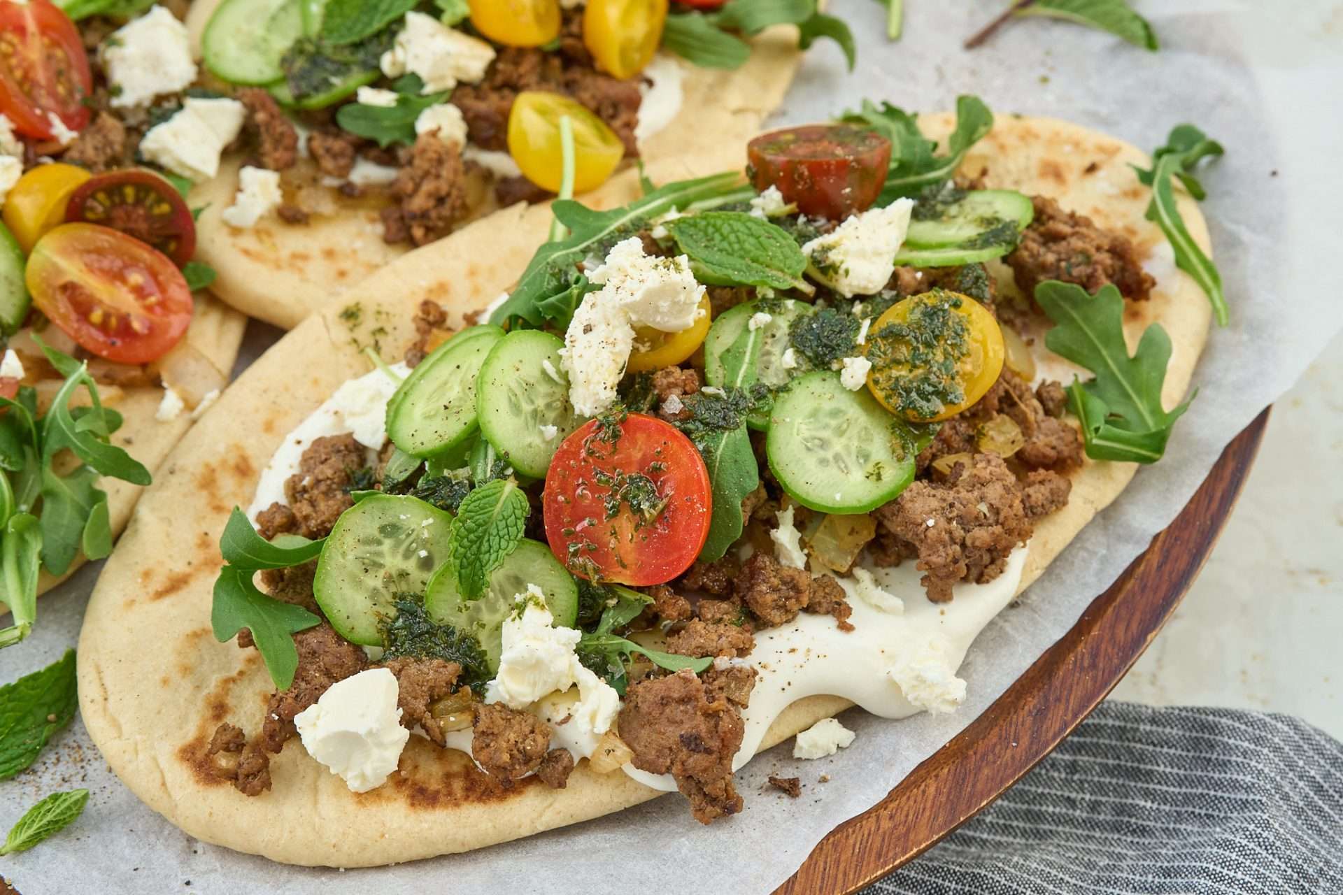 Warm flatbread topped with spiced American lamb, fresh cucumbers, cherry tomatoes, arugula, feta cheese, and a drizzle of mint oil
