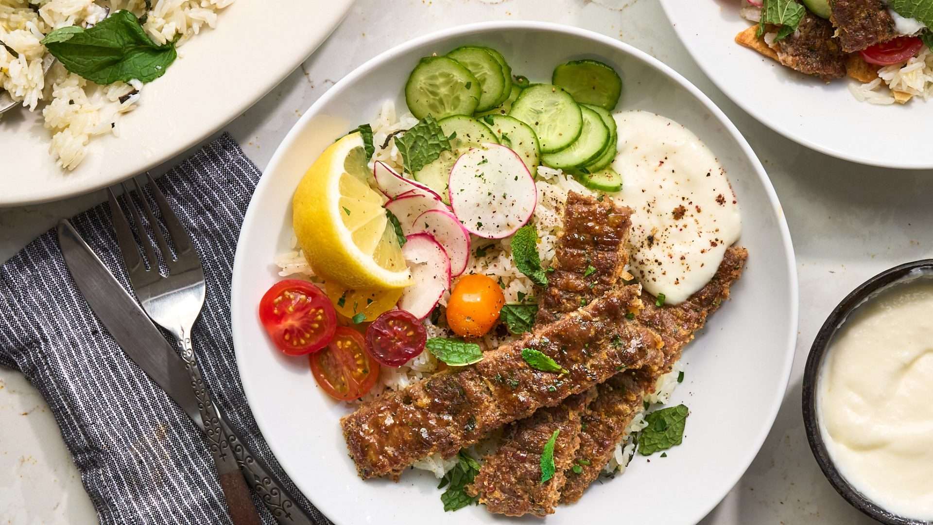 Sheet pan American lamb fajitas served on a warm tortilla with sautéed peppers and onions, sliced lamb, avocado, jalapeños, cilantro, and crumbled cheese, with lime wedges on the side.