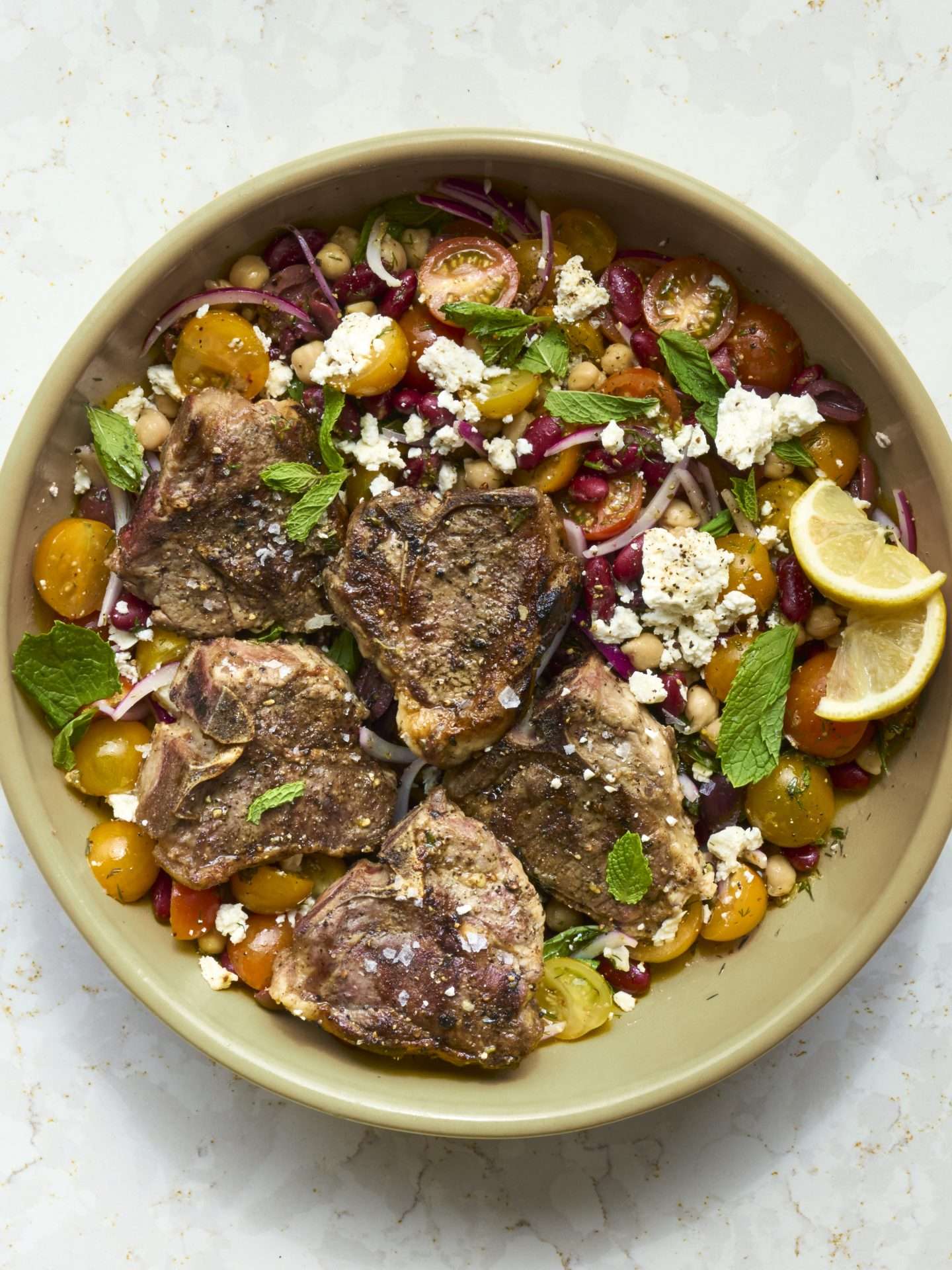 Sheet pan American lamb fajitas served on a warm tortilla with sautéed peppers and onions, sliced lamb, avocado, jalapeños, cilantro, and crumbled cheese, with lime wedges on the side.