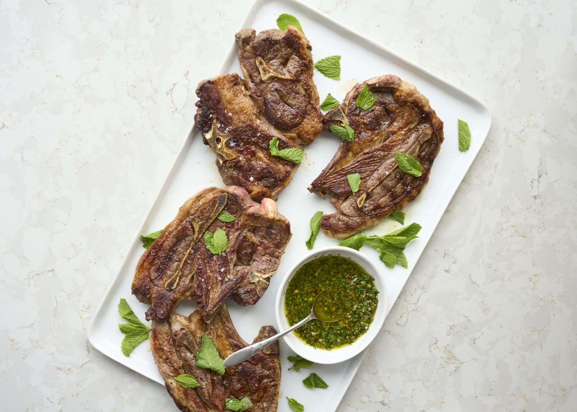 Sheet pan American lamb fajitas served on a warm tortilla with sautéed peppers and onions, sliced lamb, avocado, jalapeños, cilantro, and crumbled cheese, with lime wedges on the side.